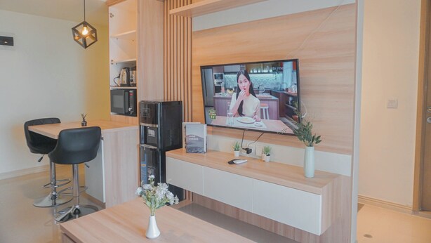 Una cocina moderna con encimera de madera, microondas integrado y televisor montado en la pared.
