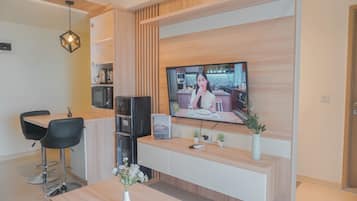 A modern kitchen with a wooden countertop, a built-in microwave, and a TV mounted on the wall.