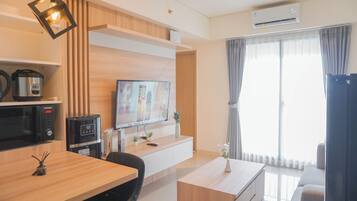 A modern living room with a flat-screen TV, wooden furniture, a coffee maker, and a large window with curtains.