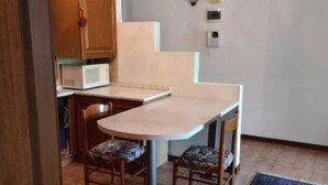 A compact kitchen with a microwave, a small table, and two chairs. - Two-room apartment Padua strategic area bookable minimum 7 nights max 20 nights. (Padova)