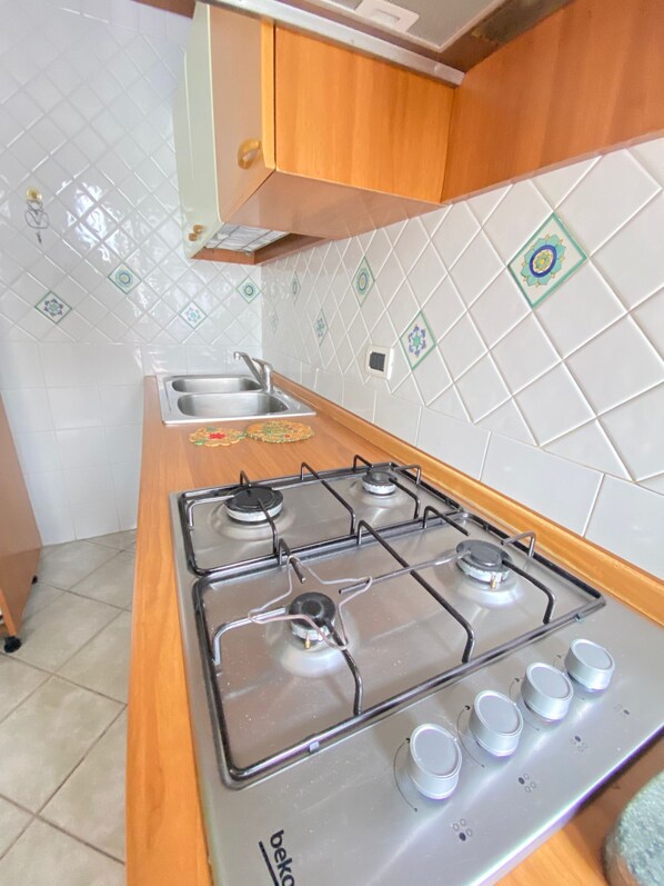 Una cocina con estufa a gas, un fregadero y un armario.