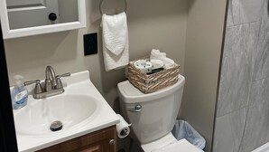 Ein Badezimmer mit weißem Waschbecken, Toilette, Spiegel und Handtuchhalter.