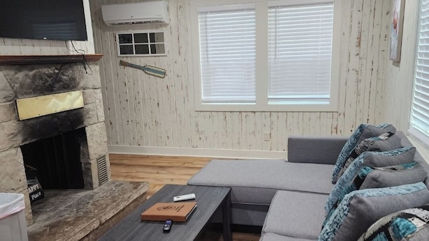 Una sala de estar con chimenea, un sofá, una mesa de centro y un televisor.