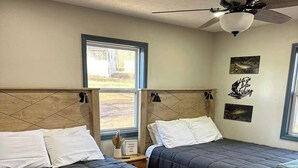 A room with two beds, a ceiling fan, and a window with a view of the outdoors. - Castaway Cabin at Fish & Fiddle Family Resort & Extended Stay (Mountain Home)