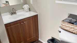 Een badkamer met een houten wastafelmeubel, een witte wasbak en toilet.