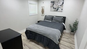 Een slaapkamer met een bed, nachtkastje en een potplant.