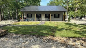 A single-story building with a dark roof, surrounded by trees and a well-maintained lawn. - Boater's Bliss at Fish & Fiddle Family Resort & Extended Stay (Mountain Home)