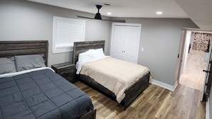 A bedroom with two beds, a ceiling fan, and a door leading to a bathroom. - Secluded Hideaway at Fish & Fiddle Family Resort & Extended Stay (Mountain Home)