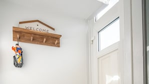 A hallway with a wooden coat rack, a welcome sign, a lattice screen, and a door.