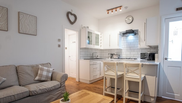 A modern kitchen with white cabinets, a central island, and a dining area with a wooden table and chairs.