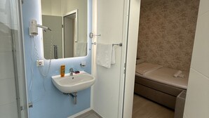 Un baño con lavamanos, espejo y zona de ducha.