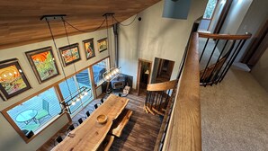 A spacious dining area with a large wooden table, multiple chairs, and a view of the outdoors through large windows.