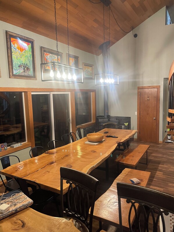 Un comedor con una mesa de madera larga, sillas negras y una puerta de madera.