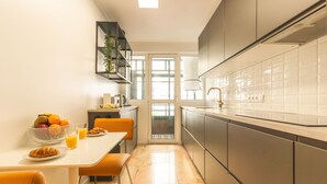 A modern kitchen with a dining area, a built-in plant shelf, and a view through a glass door. - Costa Azul by Atlantic Holiday (Funchal)