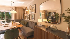 A modern dining area with a wooden table set for four, a grey sofa, and a large mirror on the wall. - Costa Azul by Atlantic Holiday (Funchal)