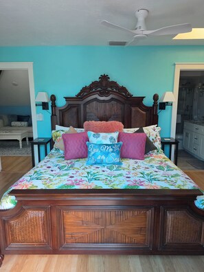 Un dormitorio con cama de madera, colcha estampada y ventilador de techo.