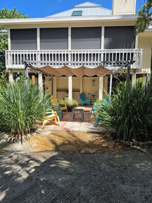 A two-story building with a covered patio area, outdoor seating, and potted plants. - Sunset Captiva 58. Charming 3-bedroom home in the heart of Captiva village. (captiva)