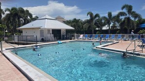 A swimming pool with lounge chairs and palm trees.