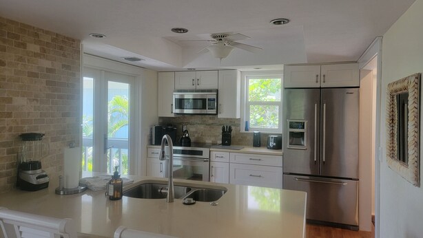 A modern kitchen with white cabinets, stainless steel appliances, and a large island with a sink.