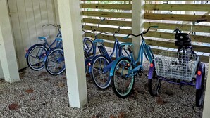 A covered bike rack with bicycles and a scooter.
