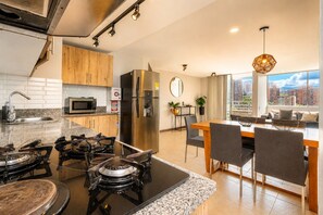Una cucina moderna con piano cottura a gas, frigorifero in acciaio inossidabile e zona pranzo con vista sulla città.