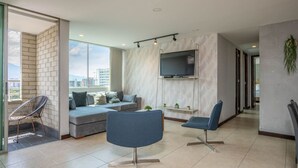 A modern living room with a sofa, two chairs, a TV mounted on the wall, and a balcony with a chair. - Penthouse Apt Poblado, City View, Rooftop Jacuzzis (Medellín)