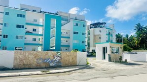 Ein modernes, mehrstöckiges Hotel mit einem auffälligen Schild 'Marina Beach', das Balkone und eine zentrale Treppe zeigt.