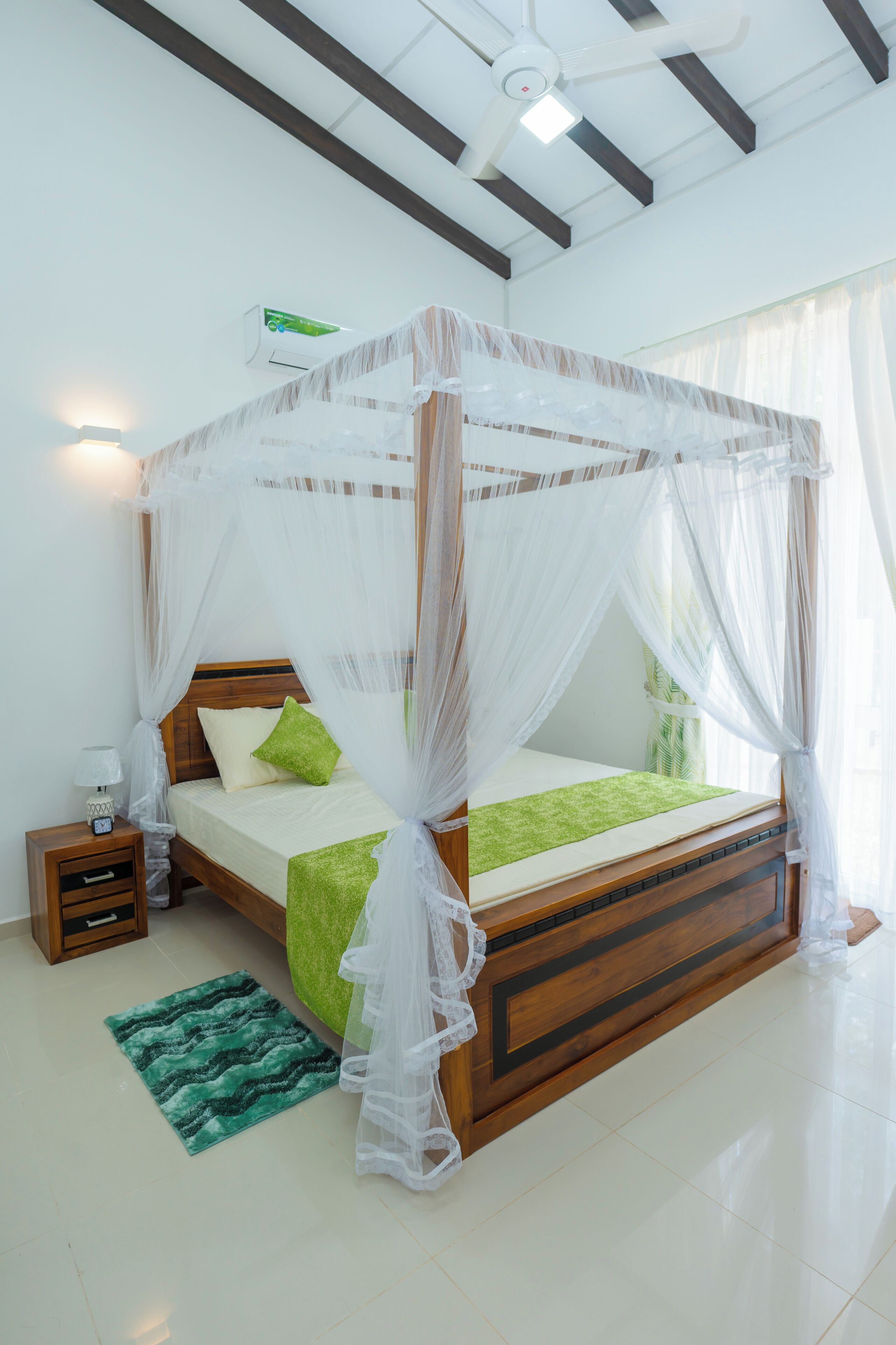 Una cama con dosel, una mesita de noche, un tapete verde y un aire acondicionado de pared.