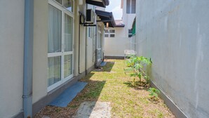 Un étroit sentier mène à un bâtiment doté de grandes fenêtres et d’un petit jardin.