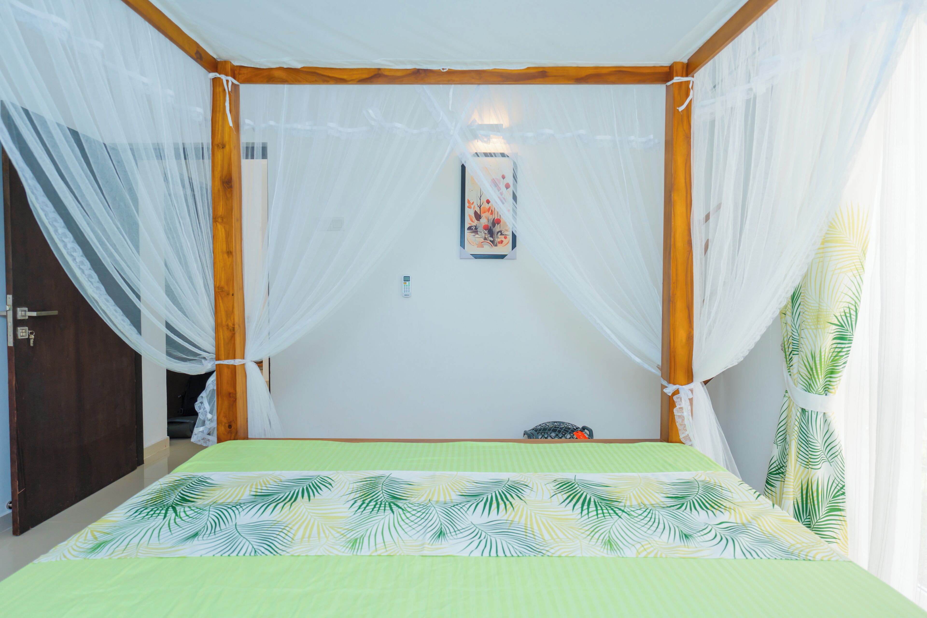 A room with a bed, a mosquito net, and a wall-mounted light fixture.