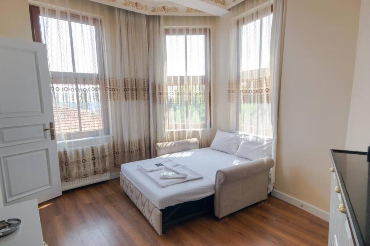 A bedroom with a bed, curtains, a window, and a door.