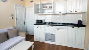 A compact kitchen with white cabinets, a microwave, and a built-in oven. - IQ Hotel Galatasaray (Istanbul)