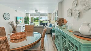 Un área de comedor moderna con una mesa redonda, sillas de mimbre y un mueble azul aguamarina con objetos decorativos.