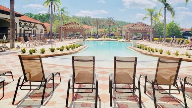 Ein Poolbereich mit Liegestühlen und einem Gebäude mit rotem Dach.