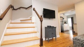 A staircase with wooden steps and a wooden handrail, a gray cabinet, and a flat-screen TV mounted on the wall. - 9 Lake Street  (Wolfeboro)
