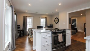 A modern kitchen with white cabinetry, a built-in oven, and a dining area with a table and chairs. - 9 Lake Street  (Wolfeboro)