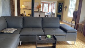 A living room with a dark gray sectional sofa, a small wooden coffee table, and a wooden floor.