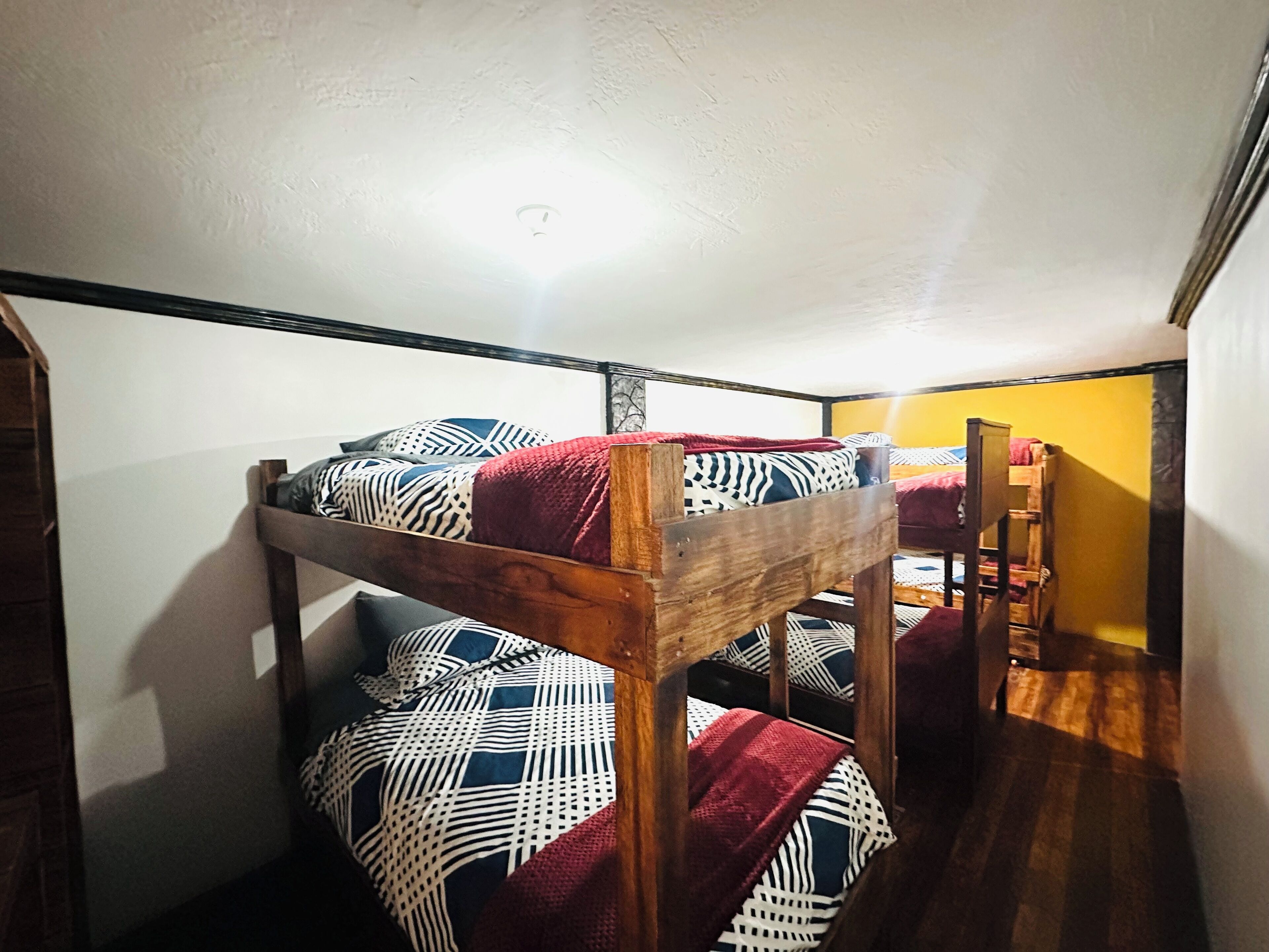 A bunk bed room with patterned bedding and a wooden ladder.