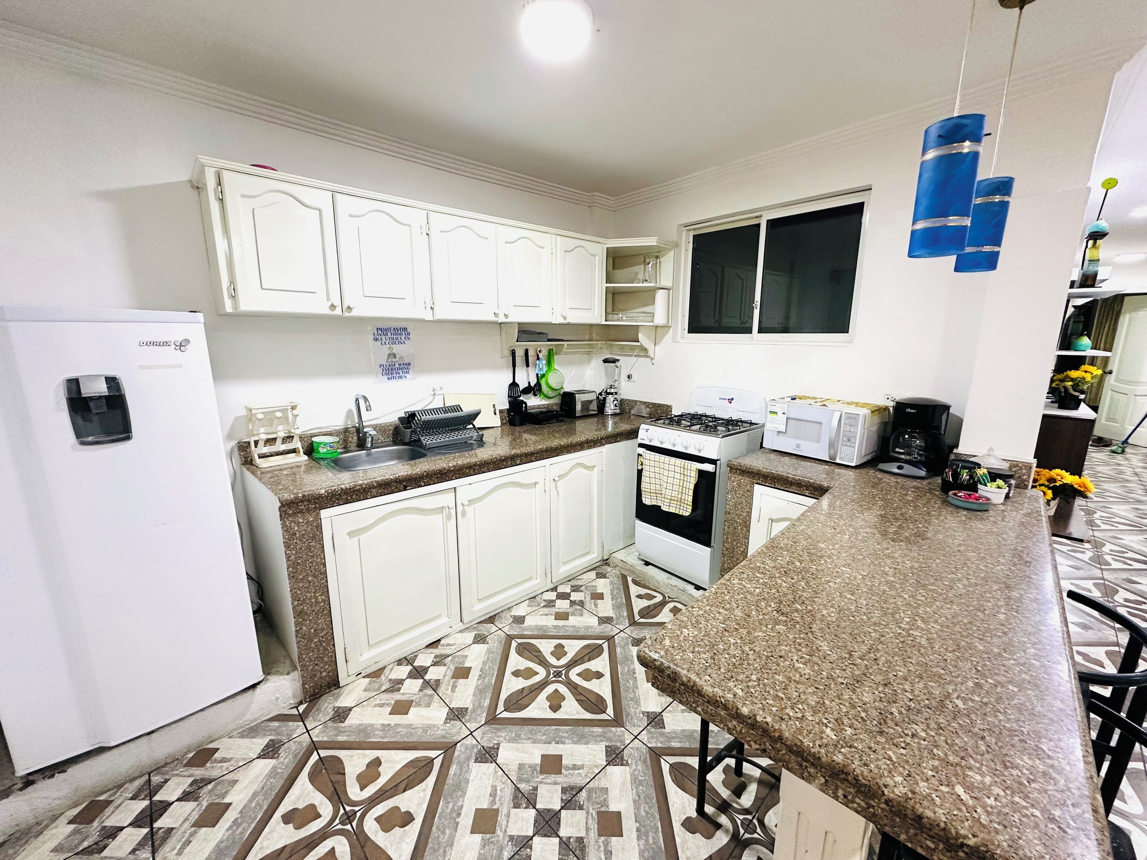A kitchen with white cabinets, a gas stove, a microwave, and a coffee maker.