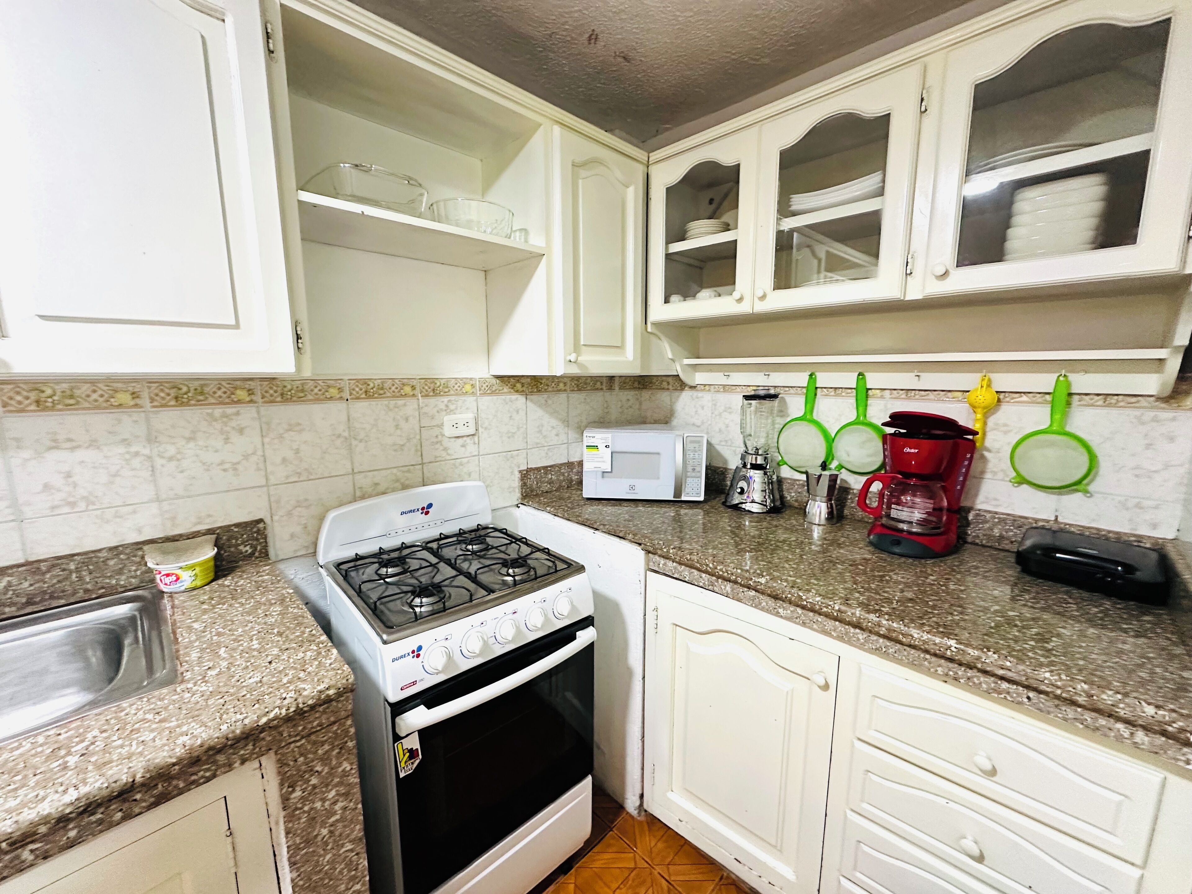 A kitchen with white cabinets, a gas stove, a microwave, and various kitchen utensils.
