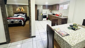 Una cocina moderna con armarios de madera oscura, un refrigerador de acero inoxidable y un área de comedor con una mesa preparada para dos.