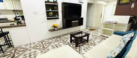 A modern living room with a sofa, coffee table, TV, and decorative items.