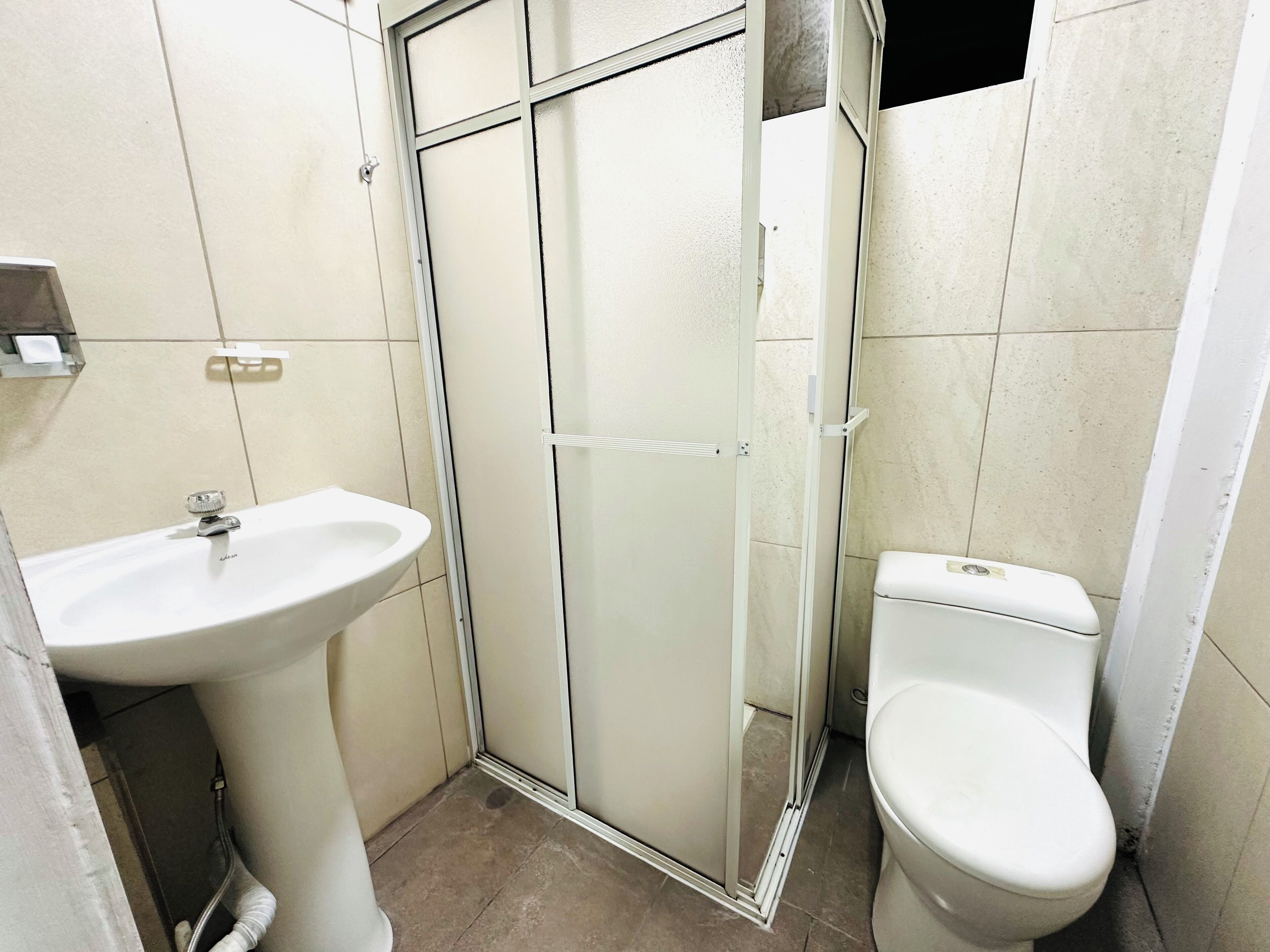 Un baño con lavamanos blanco, inodoro y cabina de ducha de vidrio.