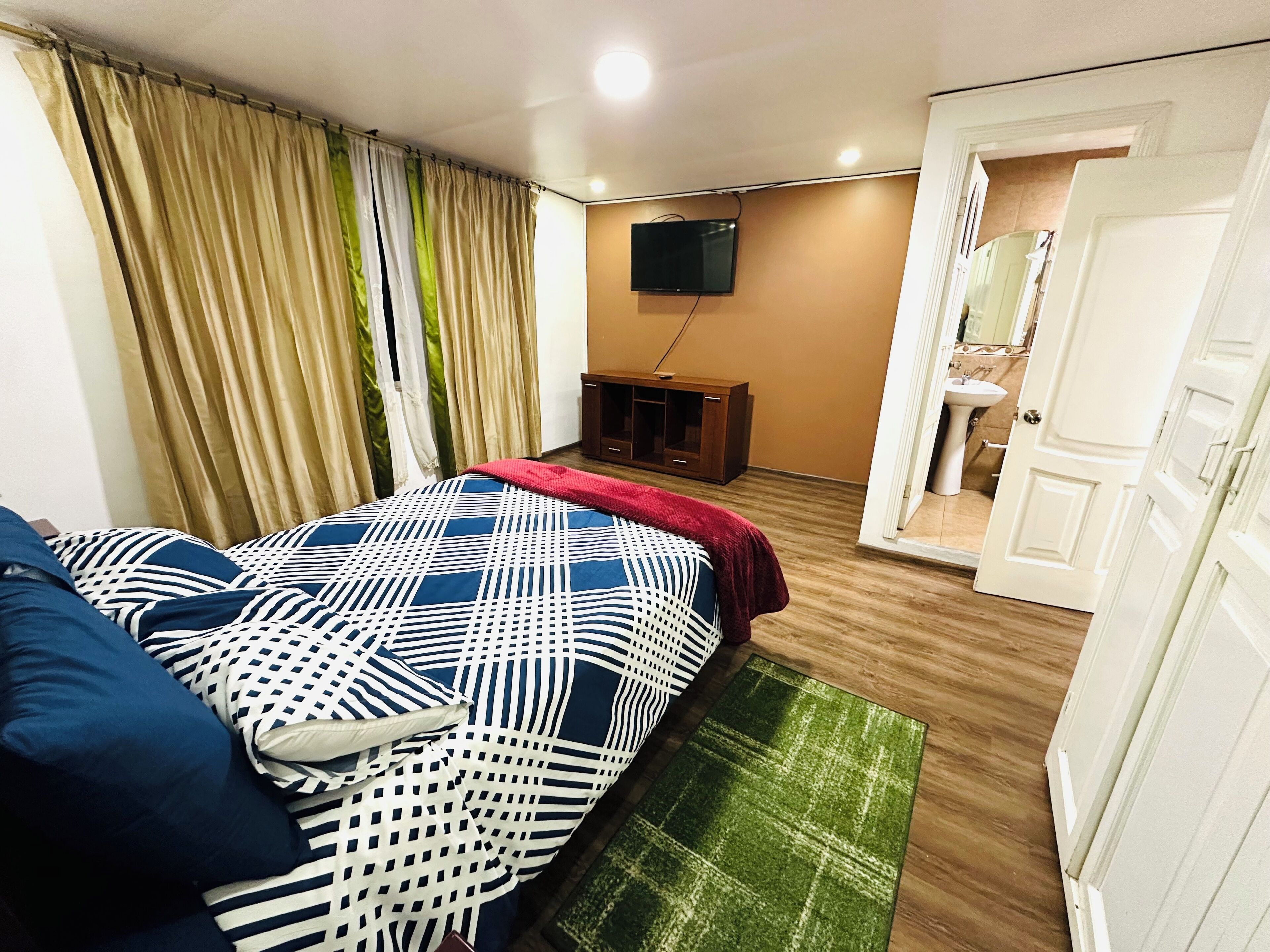 Een hotelkamer met een bed, een televisie, een houten kast en een badkamer door een geopende deur.
