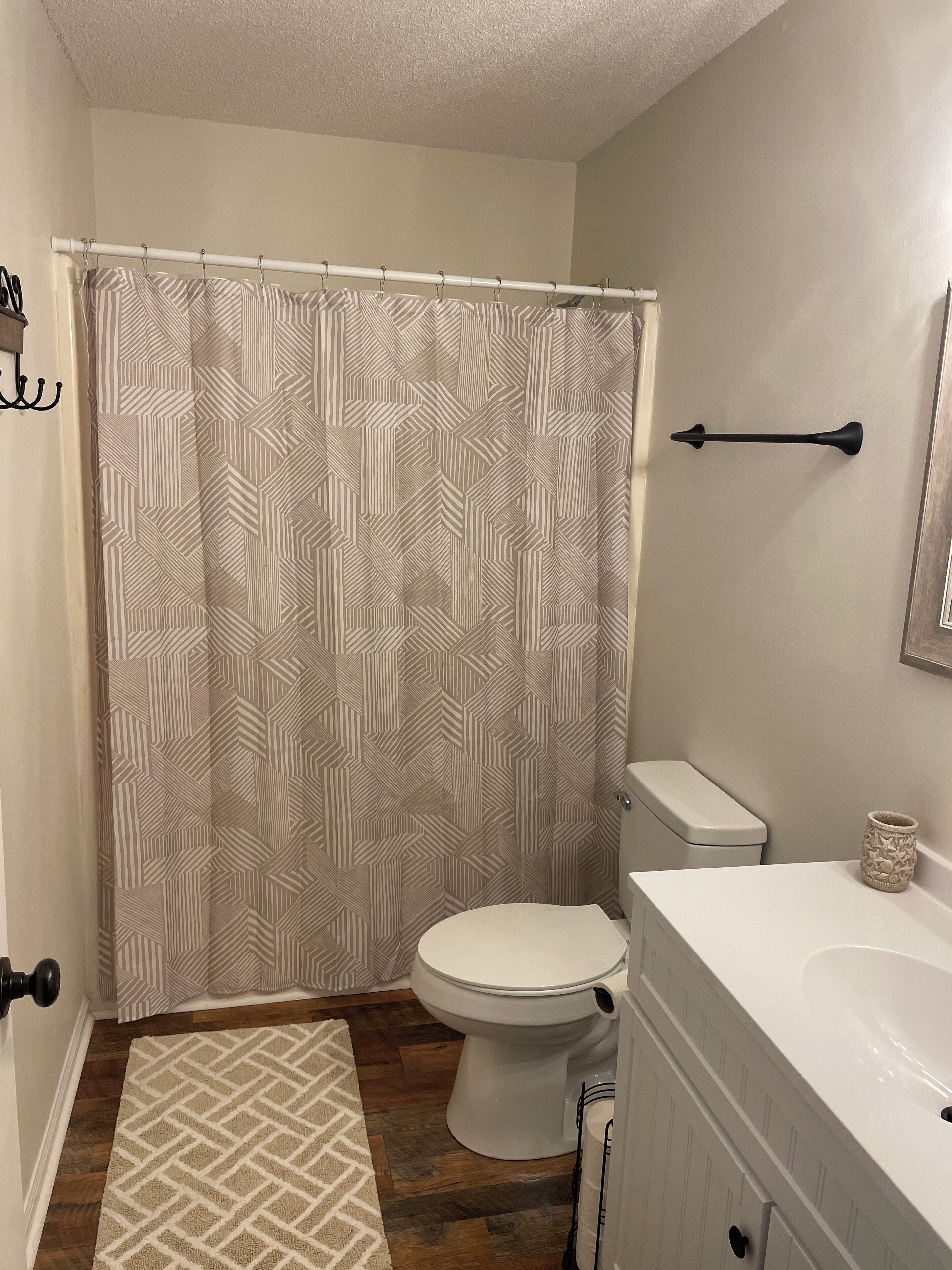 A bathroom with a shower curtain, toilet, and sink.