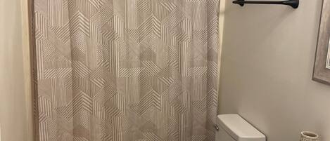 A bathroom with a shower curtain, toilet, and sink.