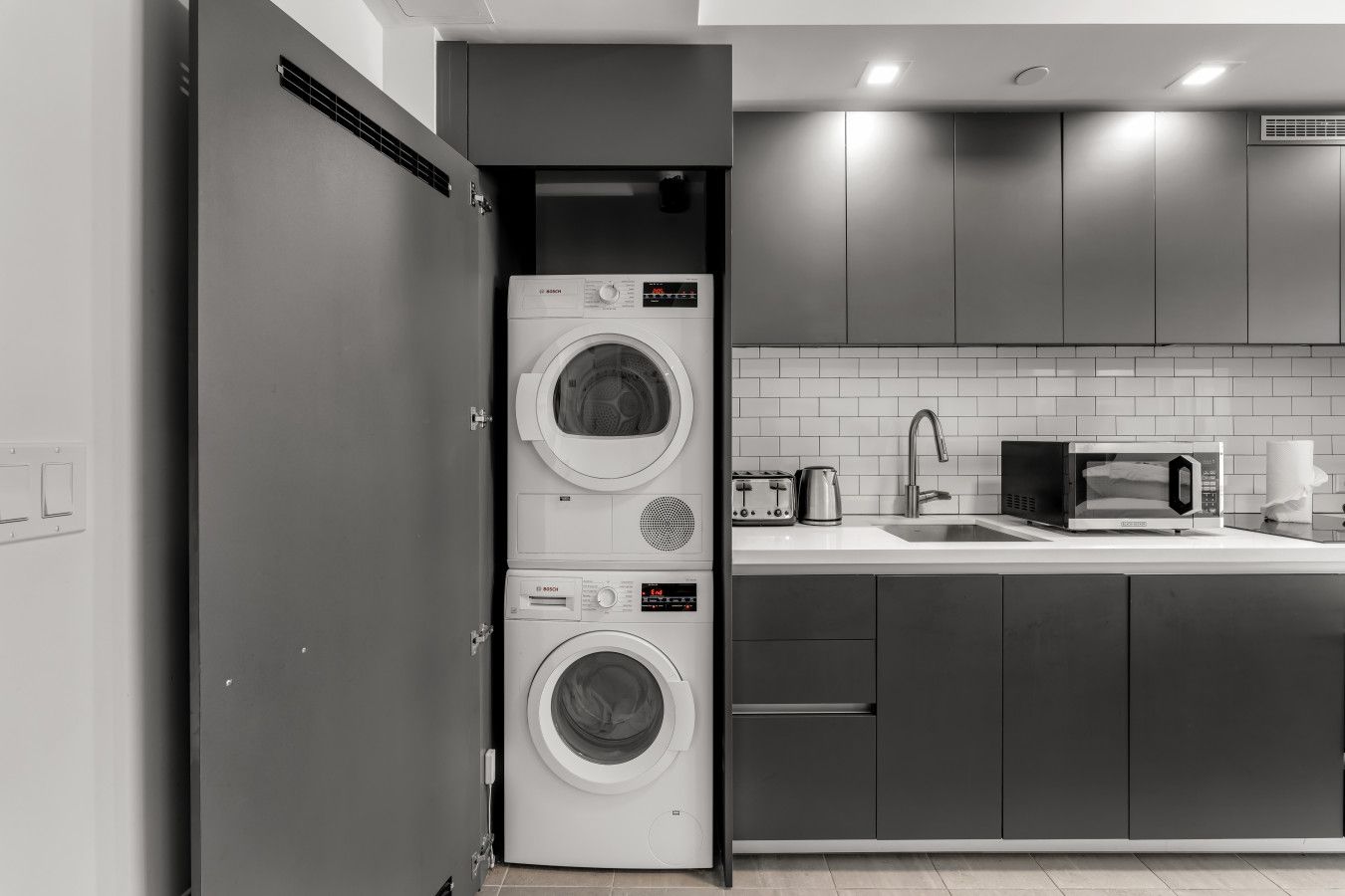 A compact kitchen with a built-in washer and dryer, a microwave, and a sink.
