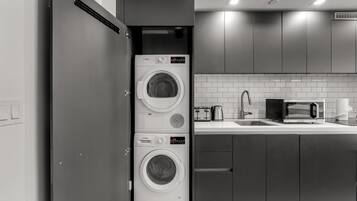 A compact kitchen with a built-in washer and dryer, a microwave, and a sink.