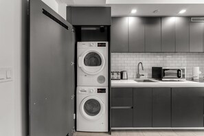 A compact kitchen with a built-in washer and dryer, a microwave, and a sink.