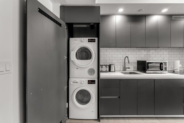 A compact kitchen with a built-in washer and dryer, a microwave, and a sink.